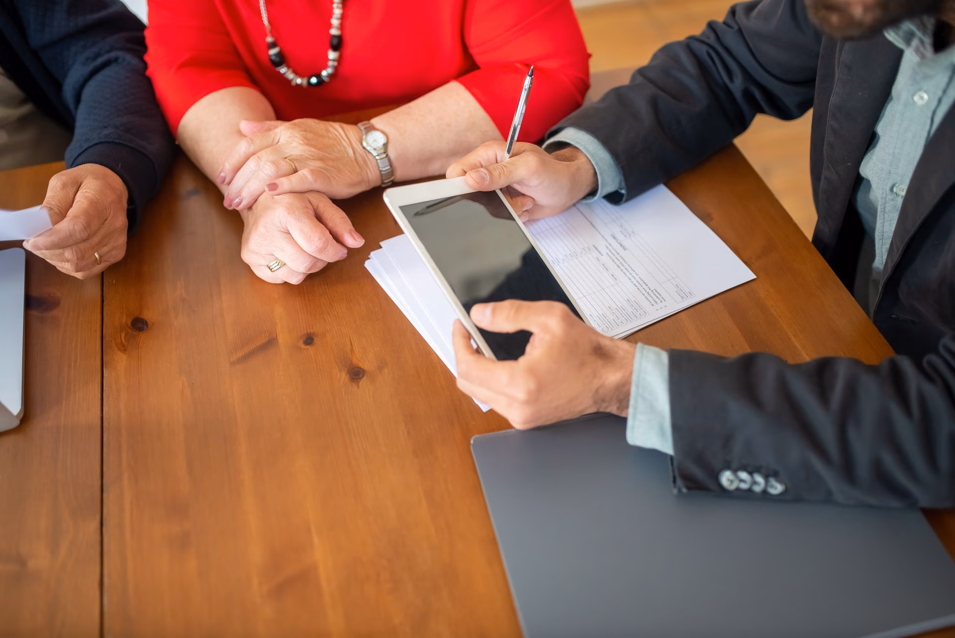 People at a table reviewing papers and a tablet during a discussion or meeting.